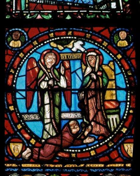 Abbot Suger at the feet of Mary at the Annunciation in a stained glass in St. Denis. Source: Wikipedia